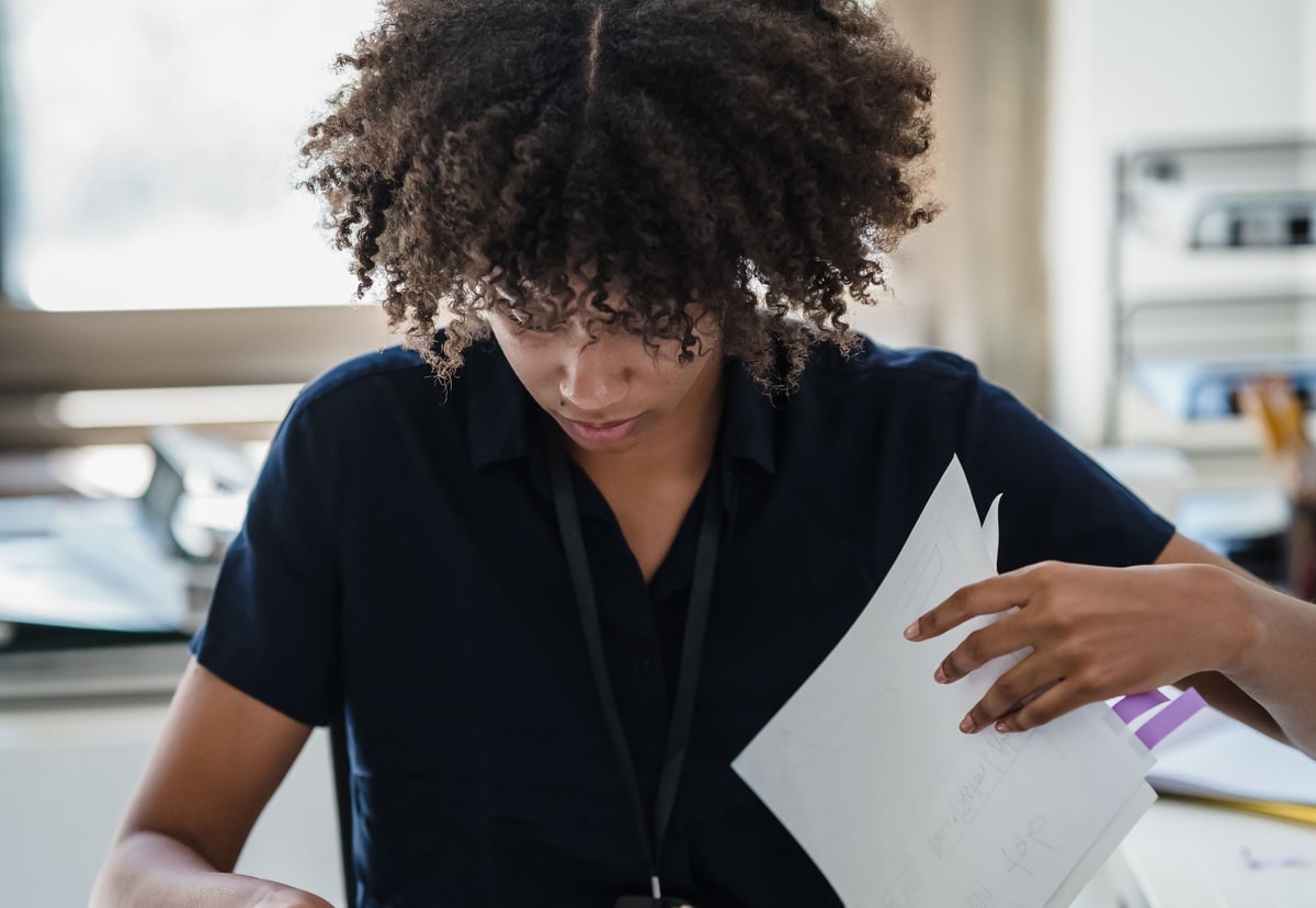 Insurance operations professional reviewing a folder of documents at a bright office desk