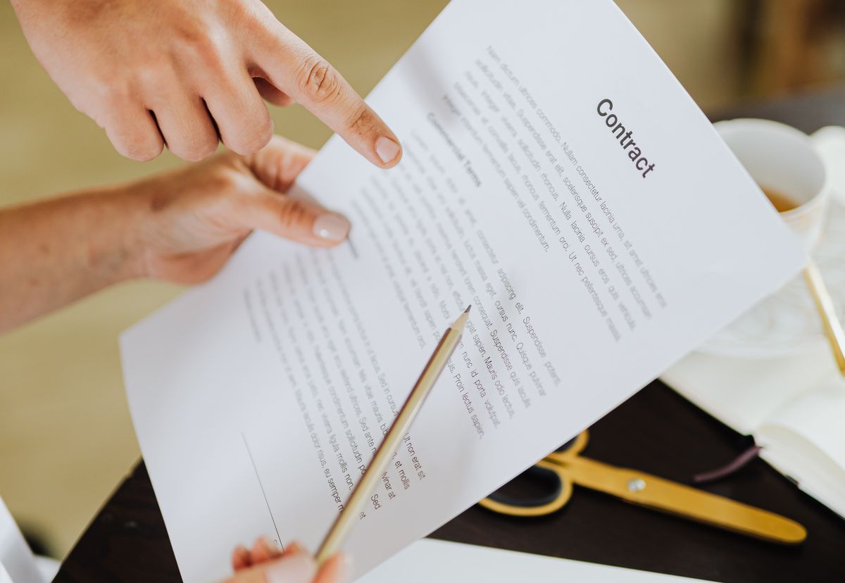 Hands reviewing a project contract together, representing clear oversight of external developers and agencies