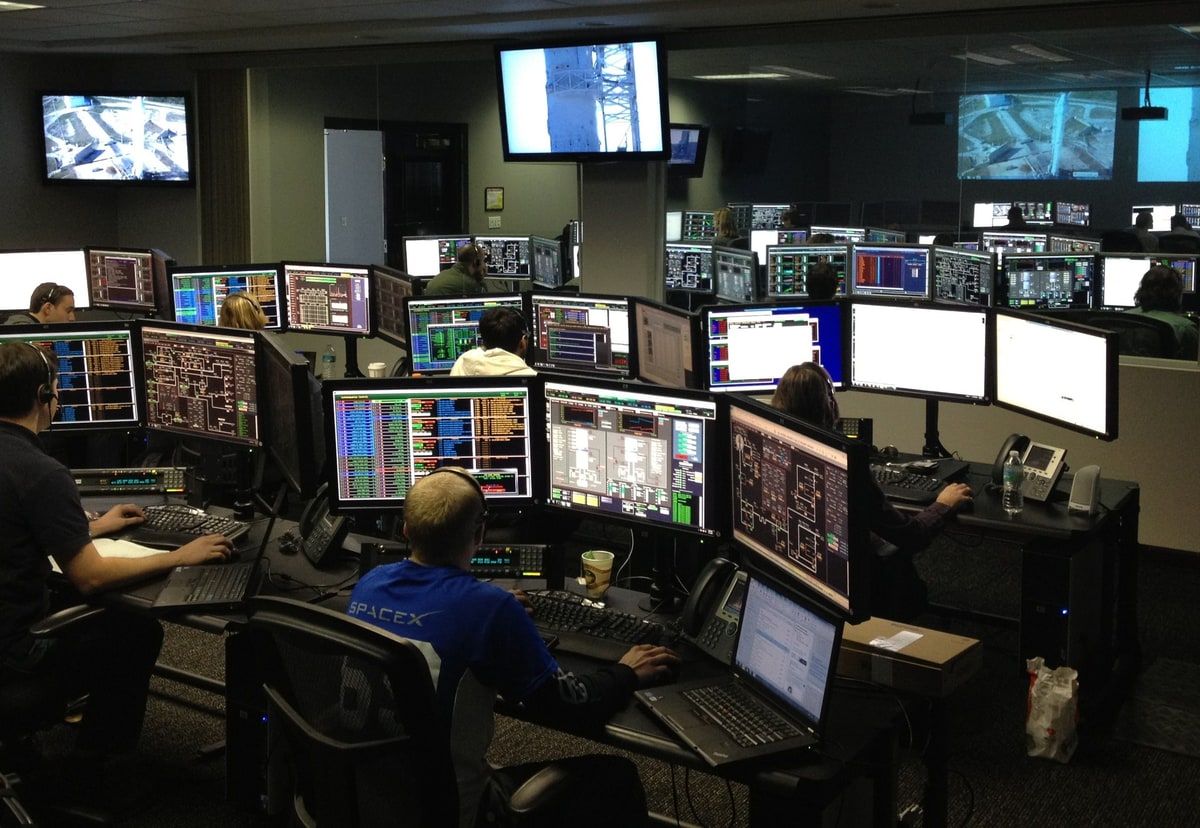 People monitoring live information across multiple screens in a control room