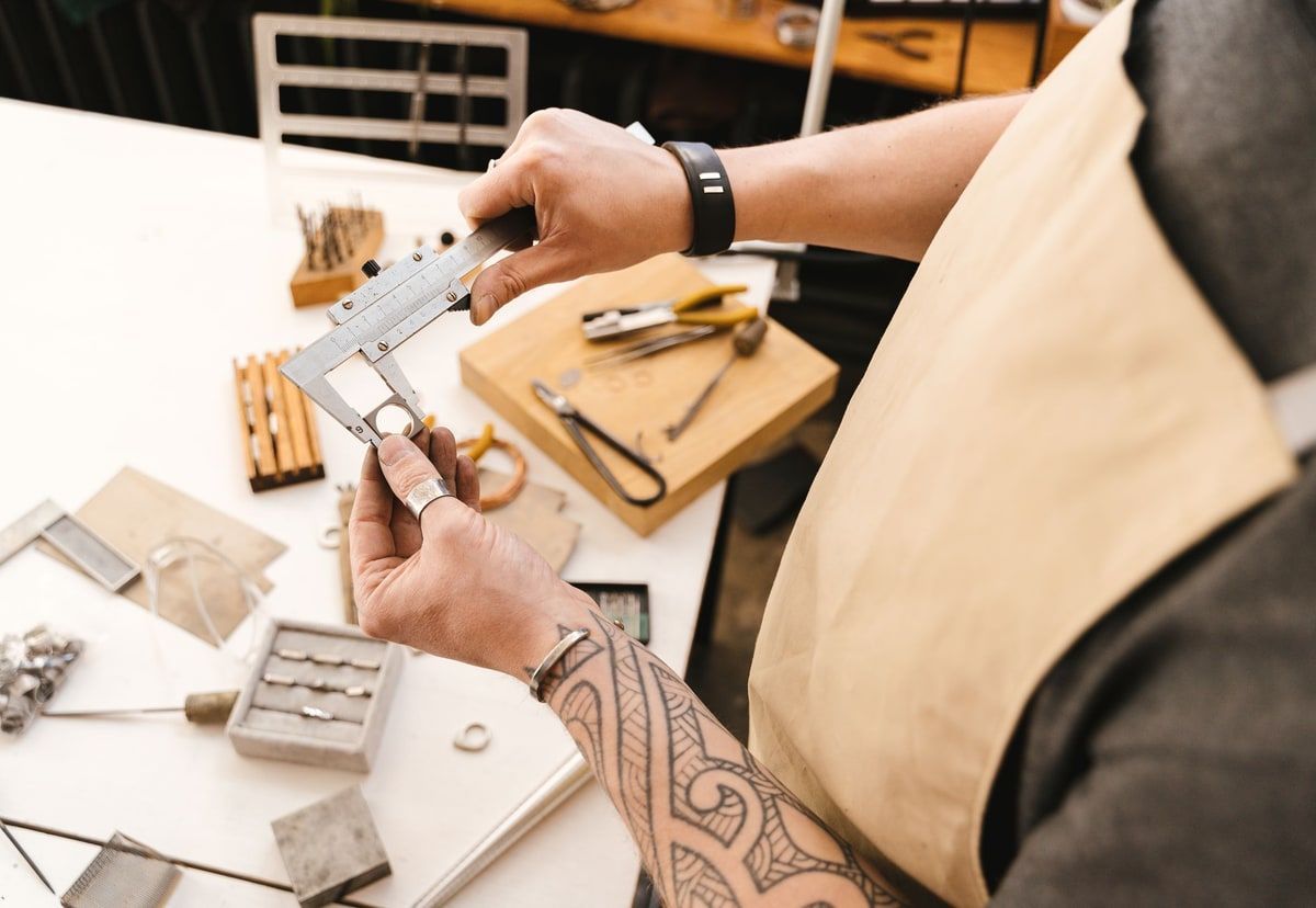 Craftsperson using a vernier caliper to check a small metal part precisely at a workshop bench