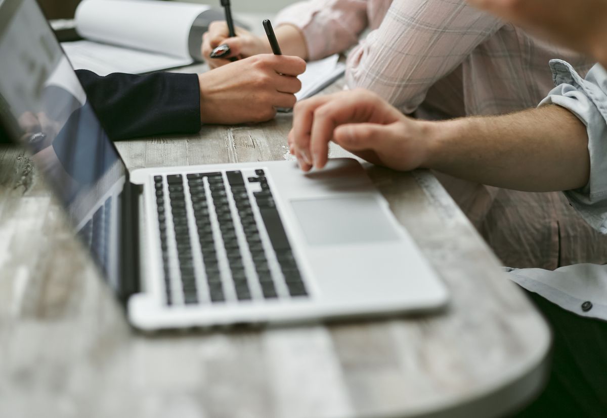 Colleagues working with documents and a laptop, representing a move from spreadsheets to a secure web portal
