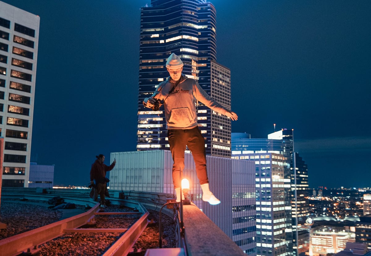 Person standing near the edge of a city rooftop representing visible technical risk