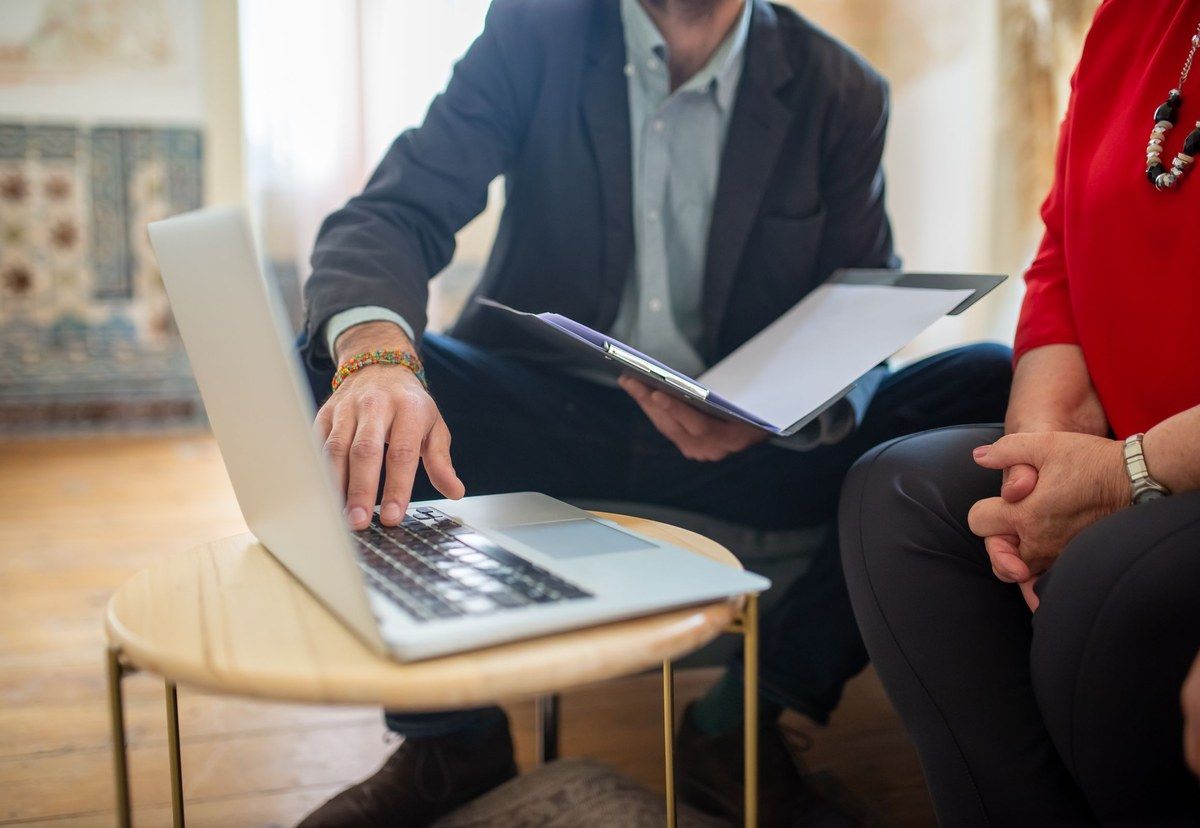 Two professionals reviewing documents beside a laptop during an office meeting.