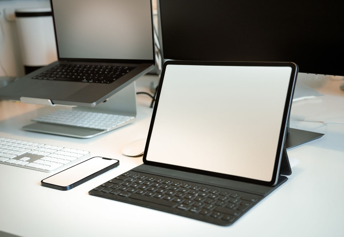 A laptop, tablet and smartphone arranged together on a bright desk as separate digital publishing surfaces