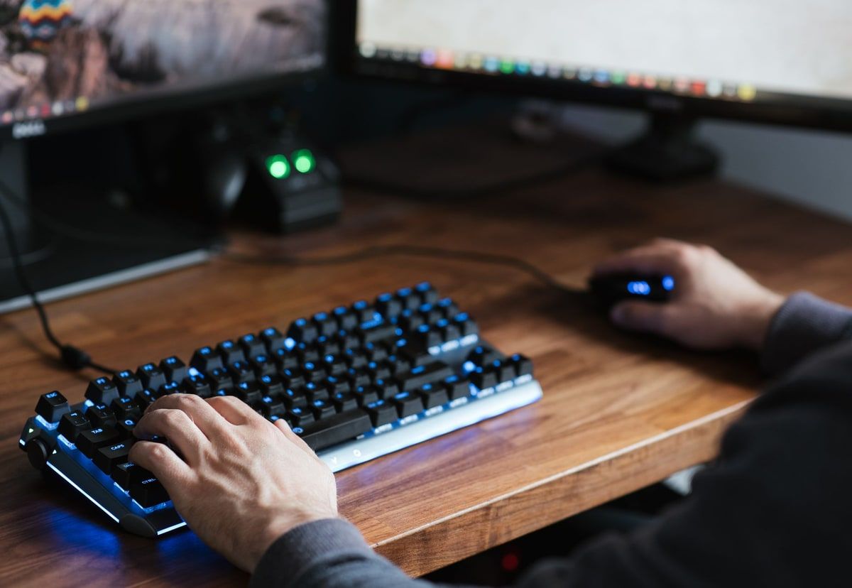 A developer using a computer at a desk with the keyboard and workspace in view